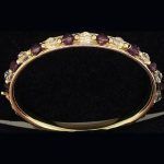 Pulsera rígida en oro amarillo con piedras preciosas de color lila y blancas
