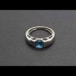 Anillo oro blanco con piedra central color azul claro