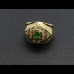 Anillo oro amarillo decorado con circonitas y en el centro una piedra de color verde
