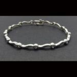 Pulsera oro blanco de 18 kt con 13 brillantes total 0,65qtes con eslabones forma de ondas 18,5 cm