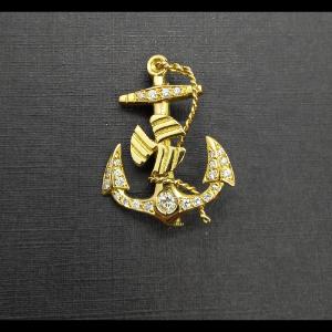 Broche oro amarillo 18k con forma de ancla decorado con puntas de brillantes y en el centor un brillante de 0,15qtes