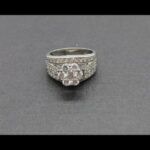 Anillo oro blanco 14 k nº14 parte central firma roseta con brillante de 0,15 qt y 6 brillantes de 0,10 qten los laterales puntas de brillantes