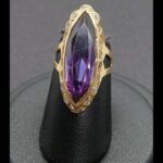 Anillo oro amarillo 18k tipo lanzadera con circonita lila rodeada de circonitas blancas nº 8