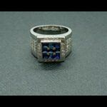 Anillo oro blanco 18k, la parte central es cuadrada con piedras azules rodeadas de puntas de brillantes nº 15