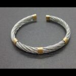Pulsera acero forma torneada semiabierta con detalles en oro amarillo