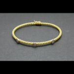 Pulsera oro amarillo 18k con forma entrelazada y decorada con puntas de brillantes engarzados en oro blanco